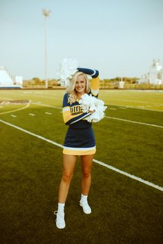 a cheerleader is posing on the field with her pom - poms in hand