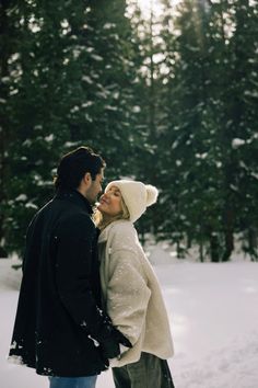 a man and woman are standing in the snow together, looking into each other's eyes