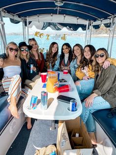 a group of women sitting on top of a boat next to each other in front of the ocean