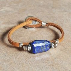 a leather bracelet with a blue stone beaded on it's end and two silver beads