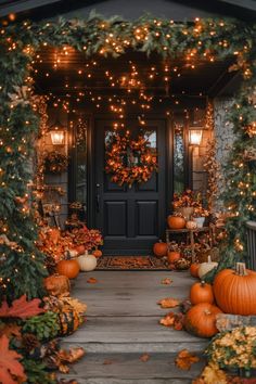 a front porch decorated for fall with pumpkins and greenery on the steps, lit up by lights