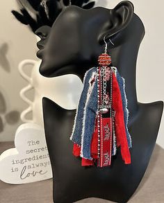 a black mannequin head with red, white and blue earrings hanging from it