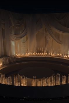 a large round room with candles lit up in the center and curtained walls behind it