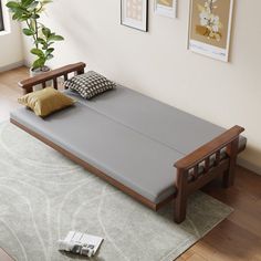 a bed sitting on top of a hard wood floor next to a wall with pictures above it