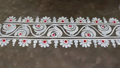 an intricately painted design on the ground with red dots and white flowers in it