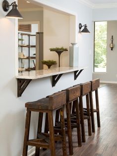 a row of wooden stools sitting next to a wall with mirrors on it's sides