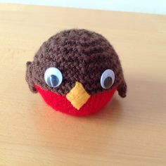 a crocheted bird sitting on top of a wooden table