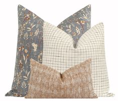 three pillows with different patterns on them, one in blue and the other in brown