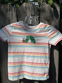 the very hungry caterpillar t - shirt is hanging on a wooden fence outside