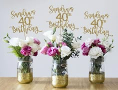 three mason jars filled with flowers on top of a table