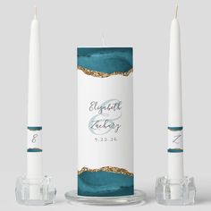 two white candles with blue and gold foil on them