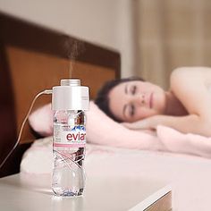 a woman laying in bed next to a bottle of e - vida on top of a table