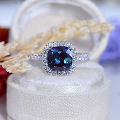 a blue diamond ring sitting on top of a white box next to other jewelry items