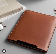 a brown leather case sitting on top of a desk next to a pair of glasses