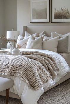 a bed with white linens and pillows in a bedroom next to two pictures on the wall