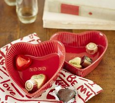 two red heart shaped dishes with chocolates in them