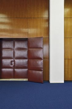 an empty room with two brown doors and blue carpet