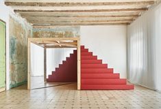 an empty room with red carpeted stairs leading up to the second floor and a green door