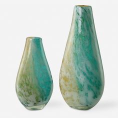 two green vases sitting next to each other on a white surface with no one in it