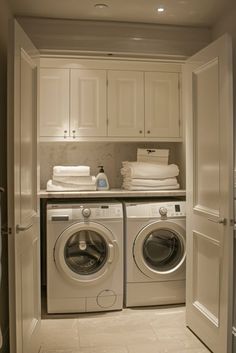 a washer and dryer in a small room with white cabinets on the wall