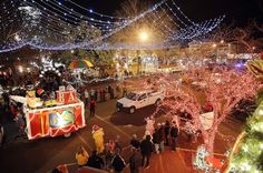 an overhead view of a street with christmas lights and people walking around the area at night