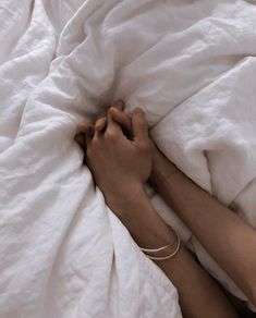 a woman is laying in bed with white sheets