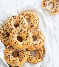 bagels with sprinkles in a basket on a white tablecloth next to two napkins