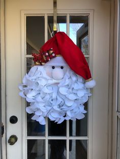 a door hanger decorated with white flowers and a red hat on it's head