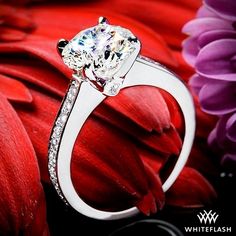 a diamond ring sitting on top of a red flower