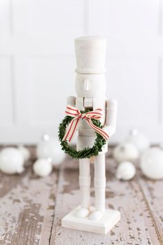 a white wooden figurine with a wreath on it