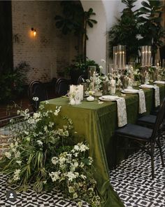 the table is set with green linens and white flowers, candles, and greenery