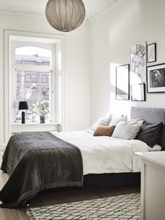 a bedroom with white walls and wood flooring has a large bed in the corner