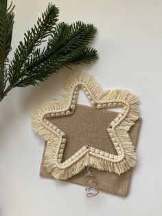 a star ornament hanging from a tree branch on top of a white surface