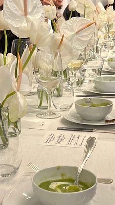 a long table is set with white flowers and silverware