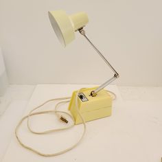 a yellow table lamp sitting on top of a white floor next to a corded phone