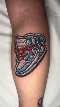 a person with a tattoo on their leg that has a shoe in the shape of a sneaker