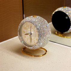 a white clock sitting on top of a counter next to a black and gold mirror