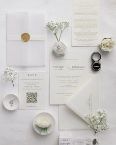 the wedding stationery is laid out with white flowers