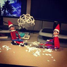 two elfs sitting on top of a desk next to a calculator and scissors