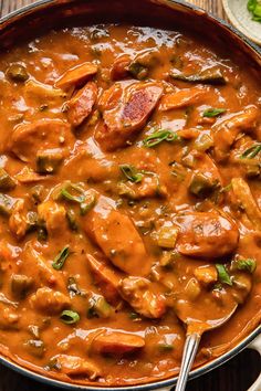 a pan filled with meat and vegetables covered in gravy on top of a wooden table