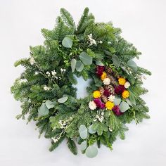 a green wreath with flowers and greenery