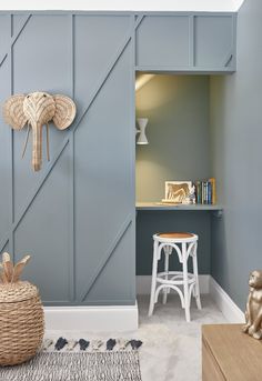 a room with blue painted walls and white stools in front of a desk area