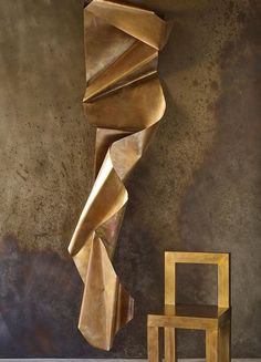 a gold sculpture next to a chair in a room