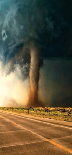 a large tornado is in the sky over an empty road