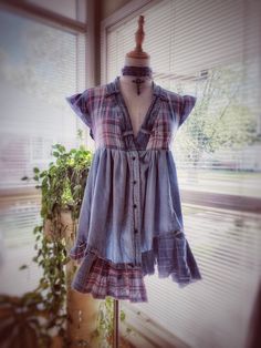 a dress on a mannequin in front of a window with a potted plant