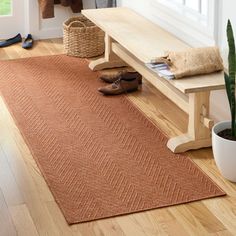 a wooden bench sitting on top of a hard wood floor next to a potted plant