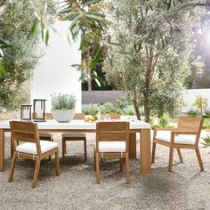 an outdoor dining table with chairs around it in the middle of a graveled area