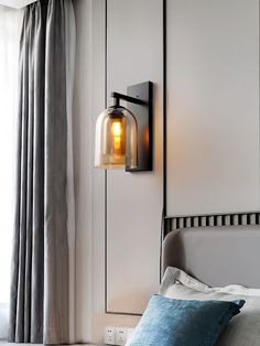 a bedroom scene with focus on the bed and wall light that has a glass shade