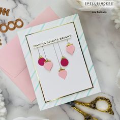 a pair of pink heart shaped earrings sitting on top of a card next to scissors