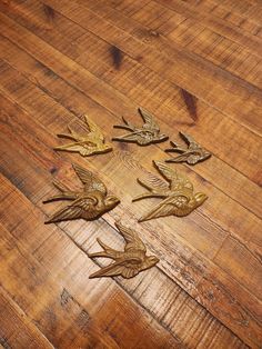 four metal birds sitting on top of a wooden floor